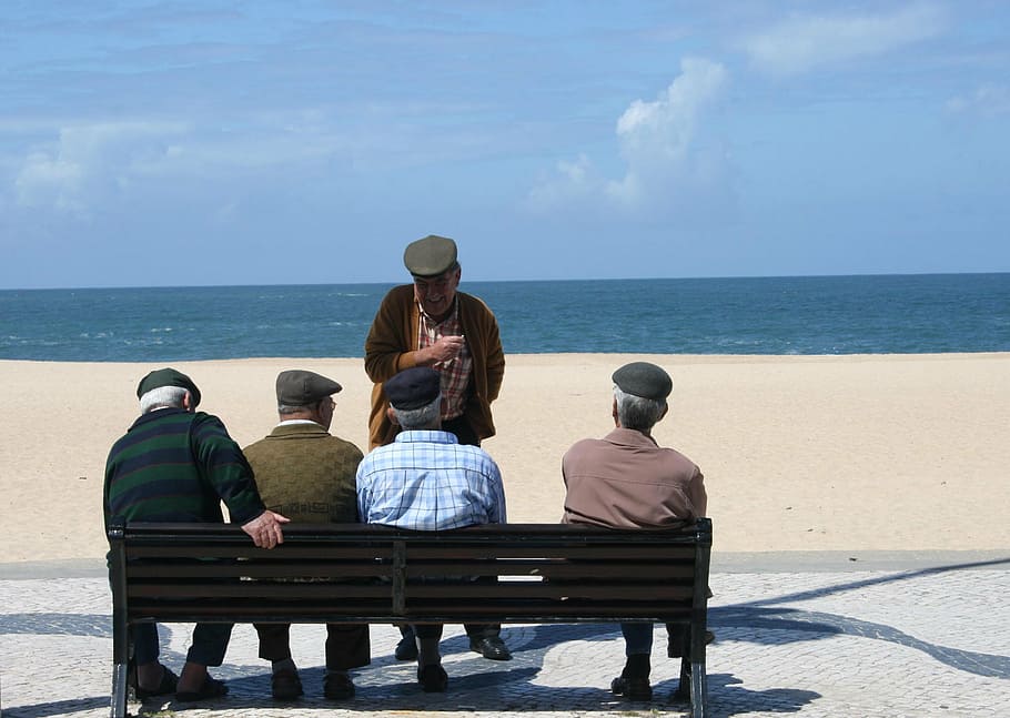 man, standing, infront, four, men, sitting, bench, daytime, old men, group of people