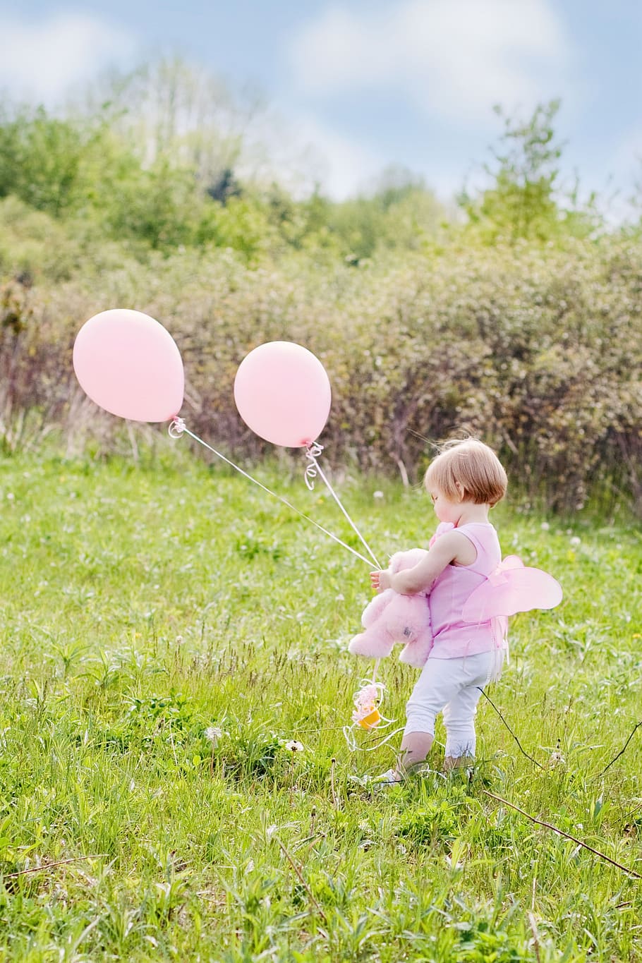 niño pequeño, vistiendo, rosa, sin mangas, arriba, sosteniendo, globos, de pie, campo de hierba, niña con globos