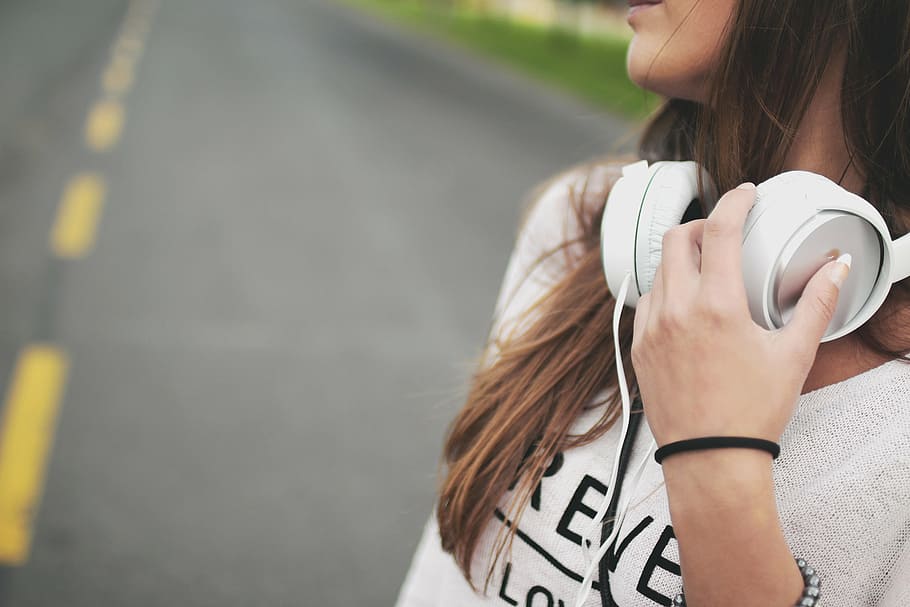 mulher, vestindo, branco, parte superior, com fio, fones de ouvido, camisa, segurando, ouvido, música