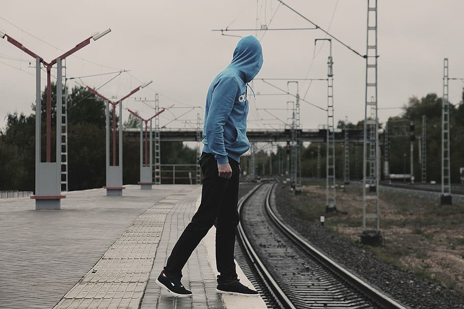 homem, vestindo, azul, moletom com capuz, andar, fotografia de estrada de ferro, dia, stand by, trem, estrada de ferro