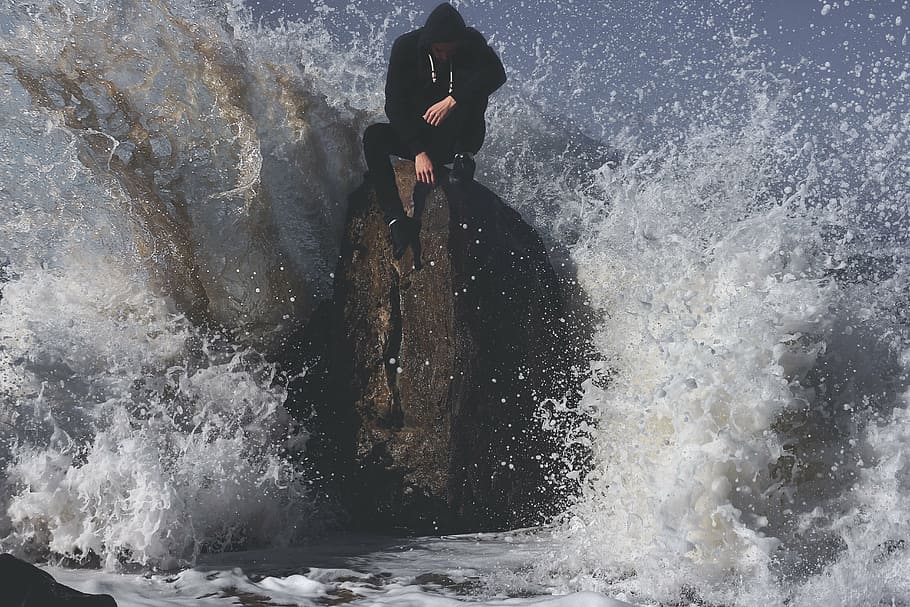 man, black, hoodie, sitting, coastal, rock, daytime, waves, ocean, sea