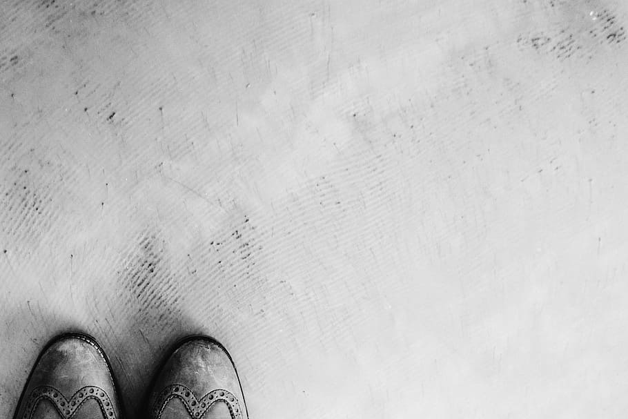 grayscale photo, wingtip shoes, ground, cement, shoes, black and white, body part, one person, human body part, shoe