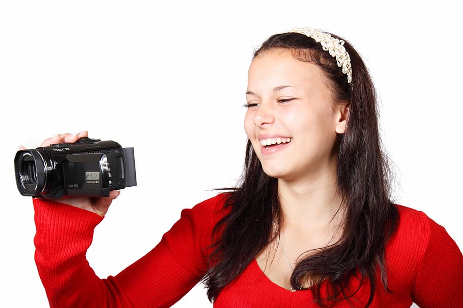 Mujer, sonriendo, sosteniendo, cámara de video, videocámara, cámara, digital, equipo, filmación, diversión
