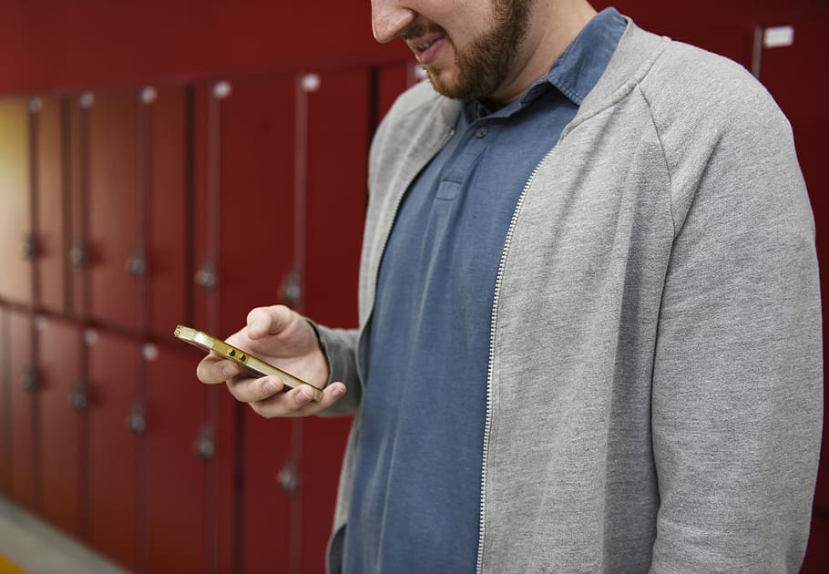 person, wearing, blue, polo shirt, gray, zip-up jacket, holding, smartphone, Adult, Break