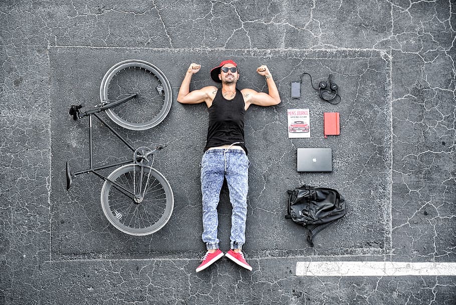 man, wearing, black, tank, top, blue, denim jeans, lying, road, bike