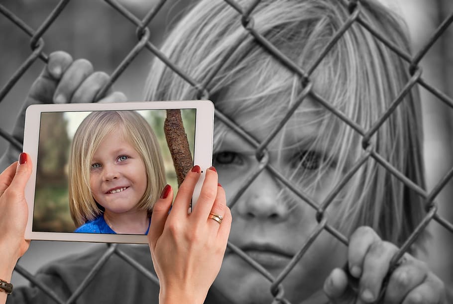 grayscale photograph, boy, holding, chain link fence, opposites, child, happy, laugh, sad, lonely
