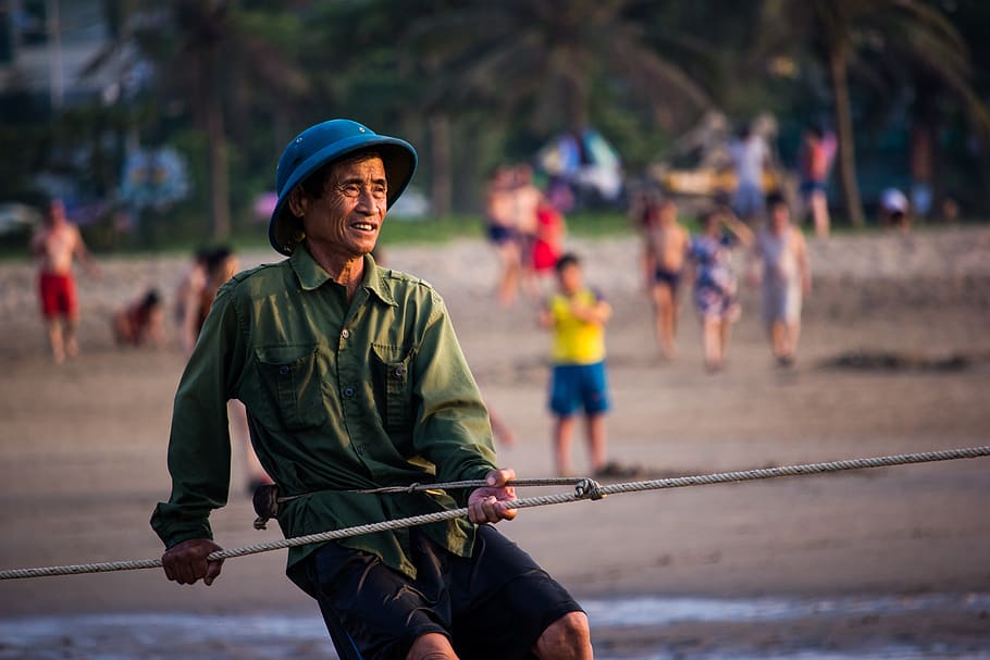 sea, dawn, fisherman, viet nam, incidental people, focus on foreground, sport, day, helmet, three quarter length