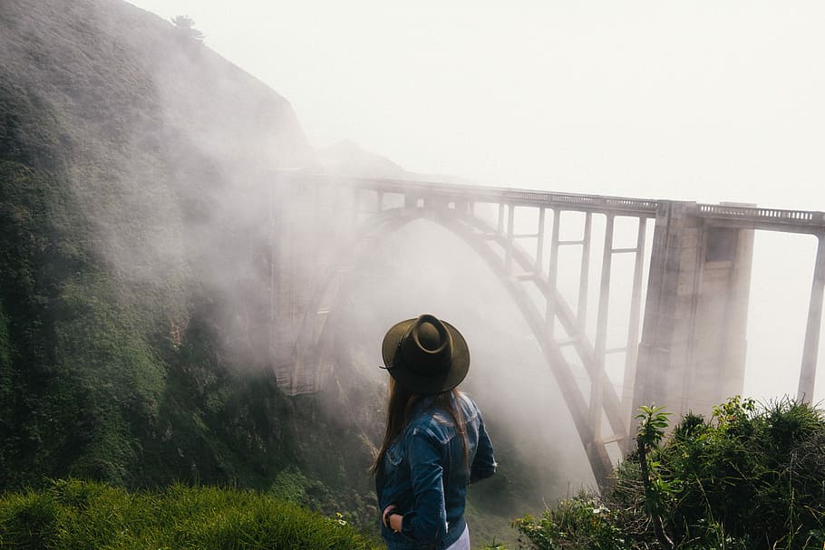 woman, cowboy hat, blue, denim jacket, standing, cliff, view, concrete, train bridge, covered