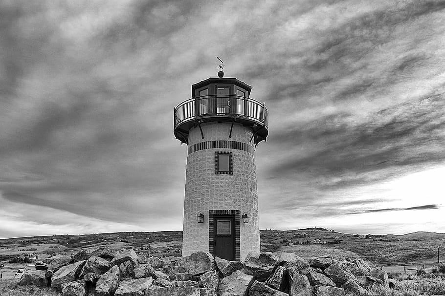 grayscale photo, lighthouse, grayscale, concrete, grey, sky, clouds, door, rocks, safety