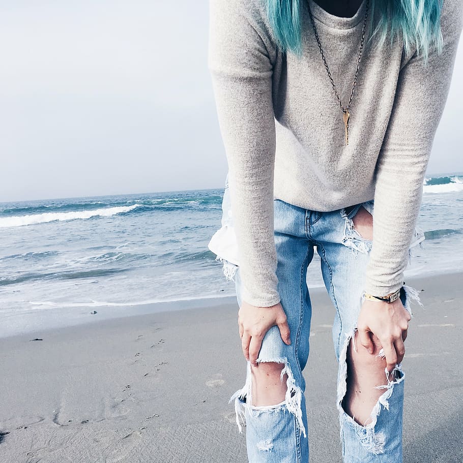 person, wearing, gray, crew-neck, long-sleeved, shirt, distressed, blue, denim jeans, standing