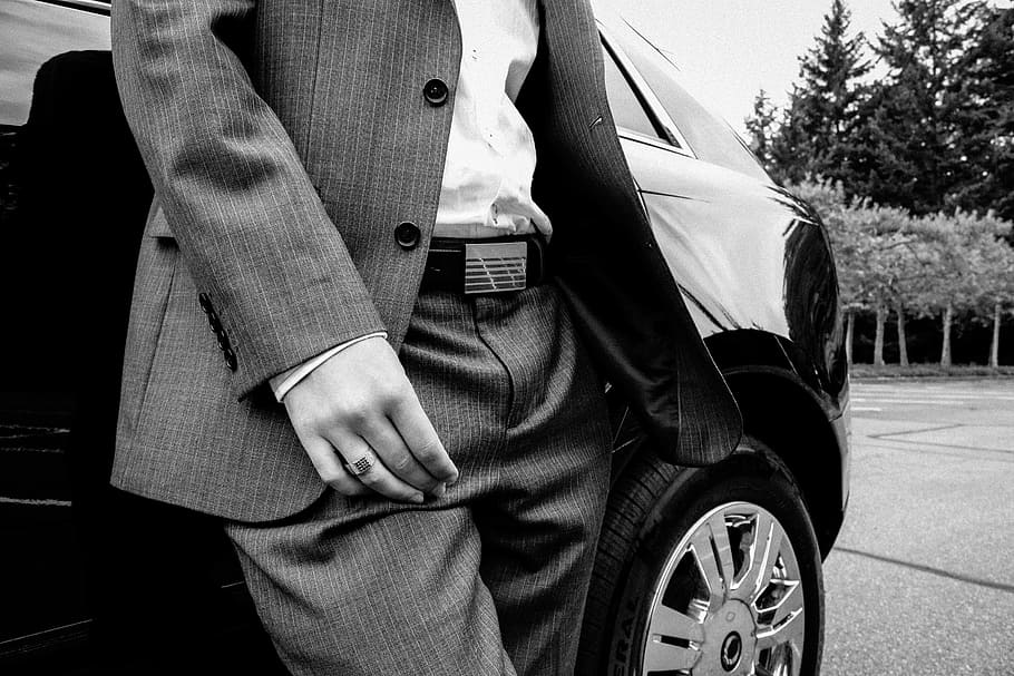 person, pinstripe suit jacket, dress pants, standing, car, grayscale, man, suit, business, businessman