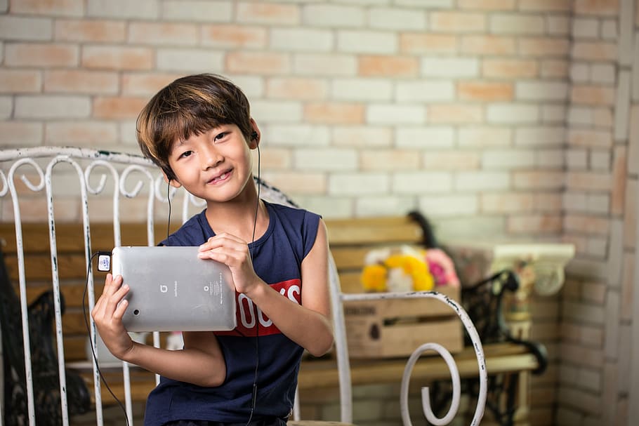 niño pequeño, sosteniendo, tableta plateada, coreano, niño, dispositivo, tableta, auriculares, música, escucha