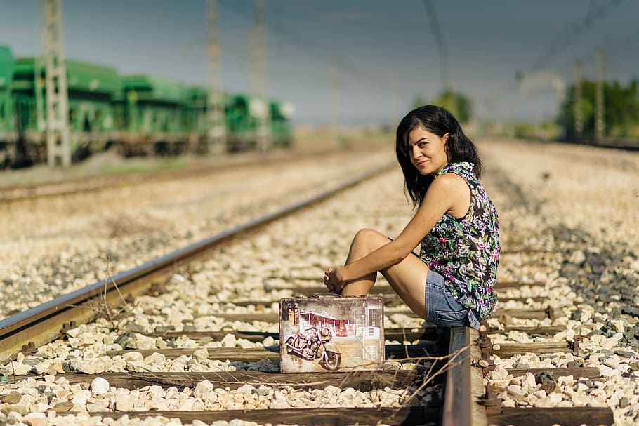 woman, wearing, black, multicolored, sleeveless, top, blue, denim shorts outfit, sitting, train railways