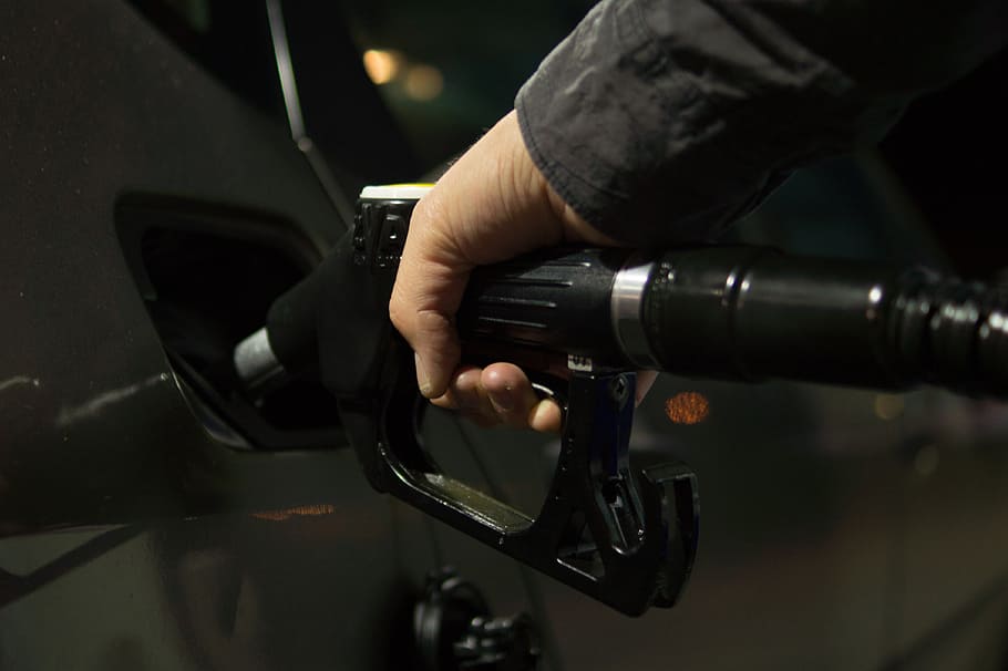 person, holding, black, fuel nozzle, mounted, car fuel tank, petrol, gasoline, diesel, gas
