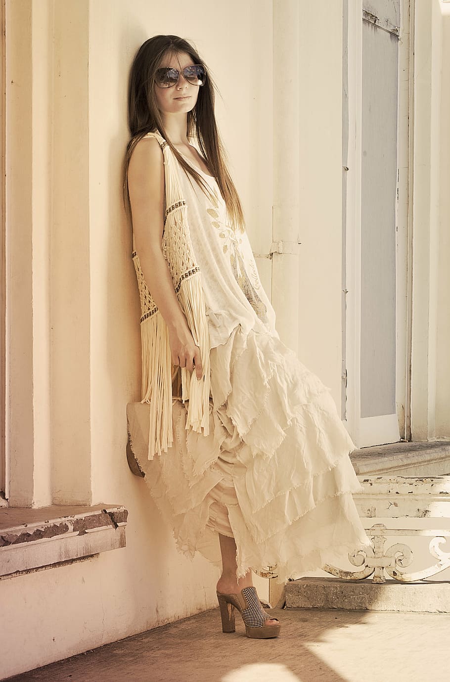 woman, wearing, white, sleeveless tier dress, leaning, wall, standing, model, summer, fashion
