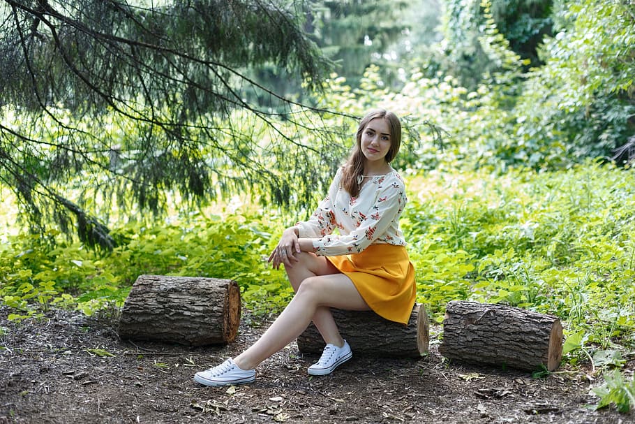 woman, wearing, white, multicolored, long-sleeved, shirt, yellow, miniskirt outfit, sitting, log