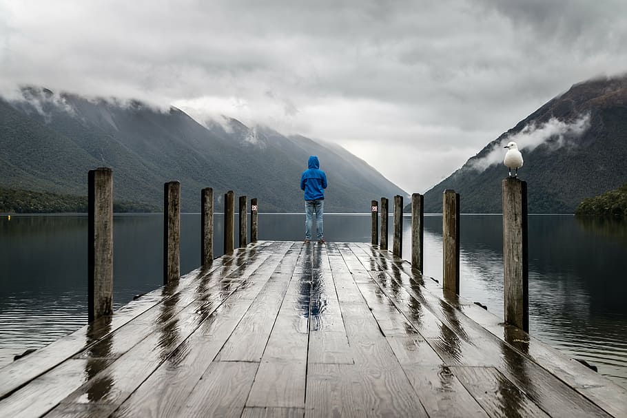 person, standing, dock, calm, body, water, mountain, highland, cloud, sky