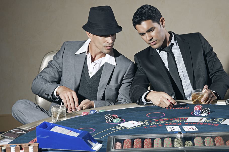 Hombre, negro, formal, traje, mesa de póquer frontal, casino, póker, jugando, estudio, apuesta
