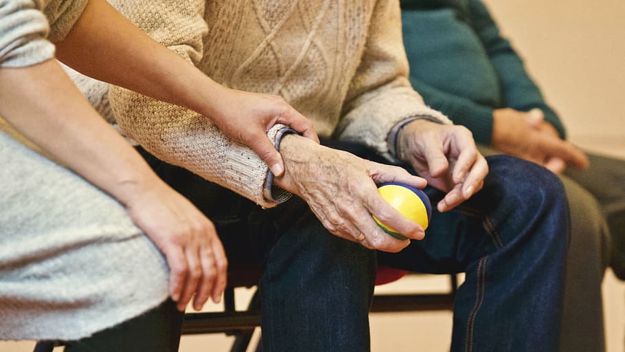person holding ball, ball, people, old, elderly, man, sitting, woman, holding hand, arm