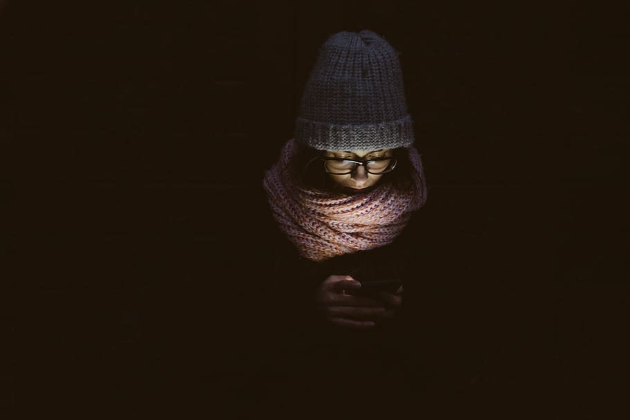 person holding device, people, woman, cold, weather, jacket, bonnet, dark, night, scarf