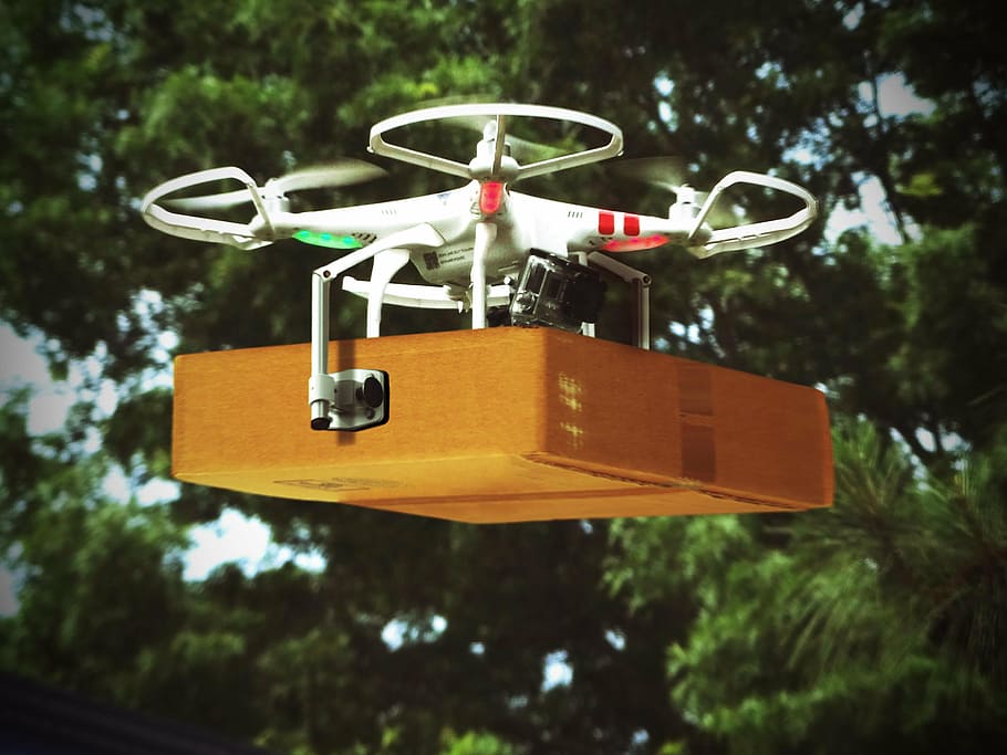 red, white, dji, phantom, drone, carrying, brown, cardboard box, hovering, mid