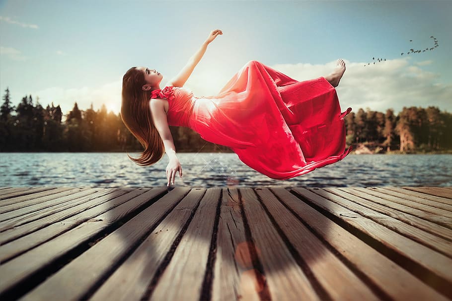 woman, red, sleeveless dress, floating, brown, wooden, dock, daytime, levitation, float