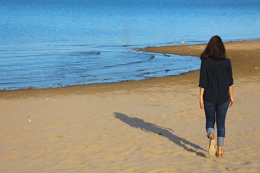 Mujer, vistiendo, azul, jeans, caminando, orilla del mar, playa, agua, verano, arena