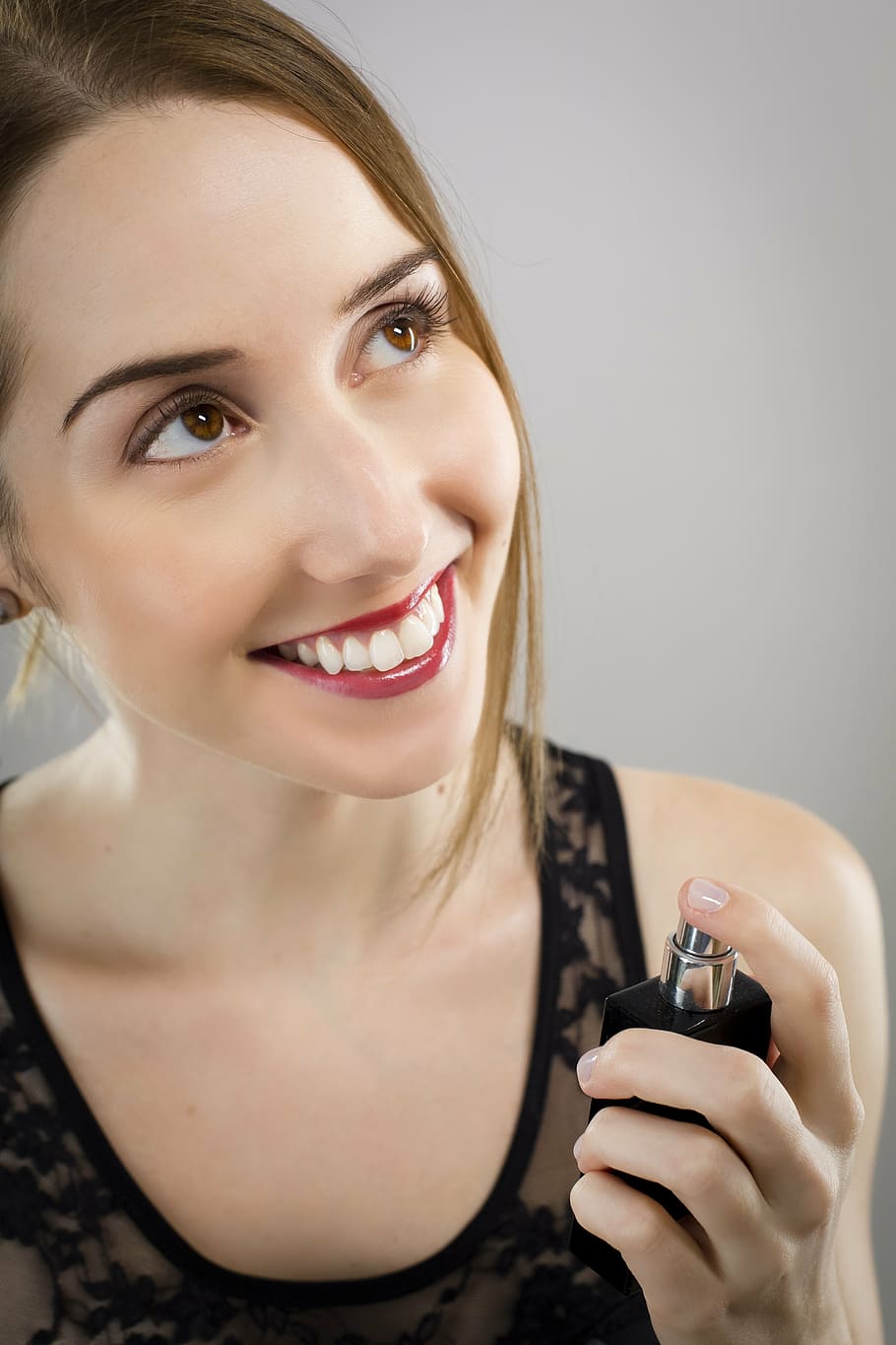 woman, wearing, black, sleeveless, top, holding, spray bottle, perfume, chic, portrait