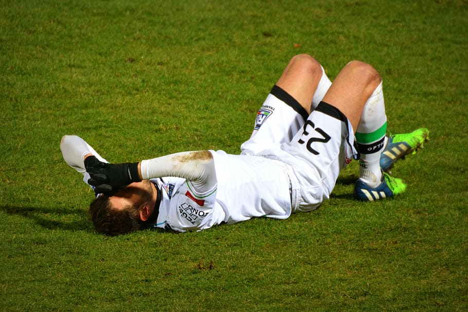 man, soccer jersey, laying, green, grass, football, injury, sports, pain, footballer