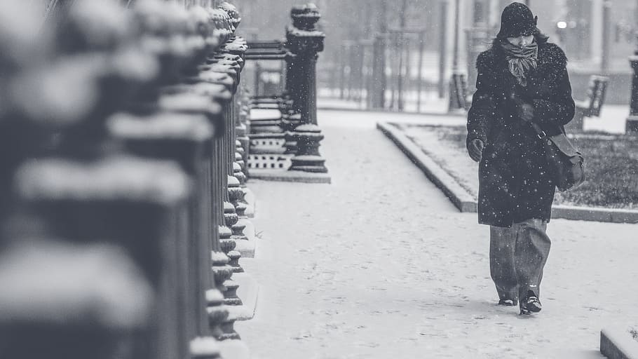 grayscale photography, person, black, trench coat, walking, across, street, winter weather, blizzard, snow