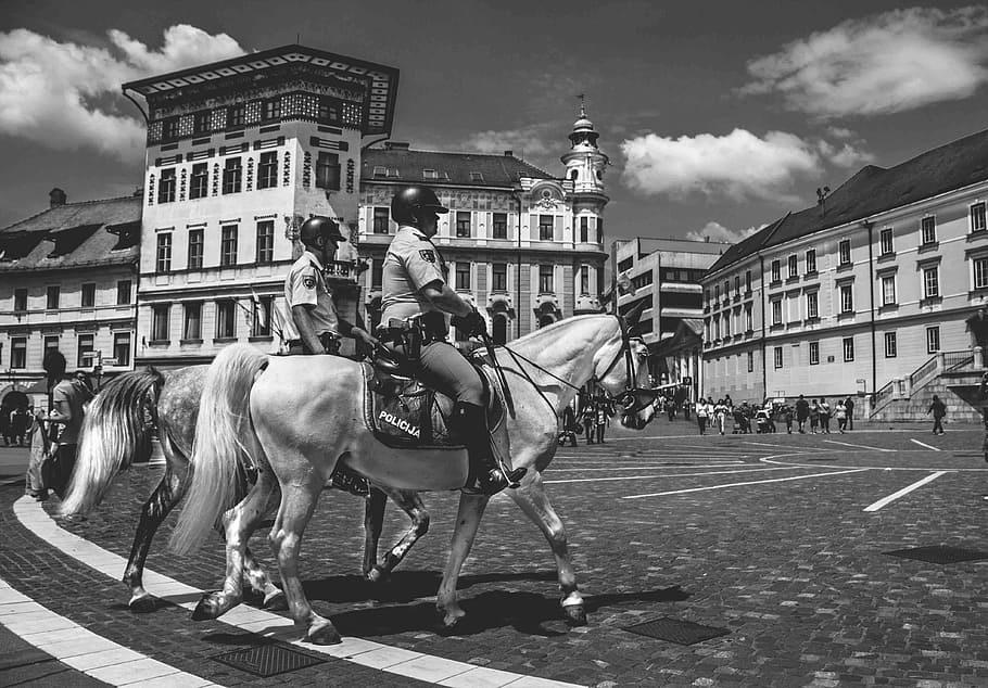 grayscale photo, two, person, riding, horses, grayscale, horsemen, architecture, buildings, city