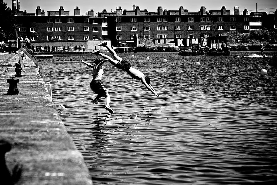 diving, swan dive, swimming, water, people, boy, girl, buildings, city, black and white