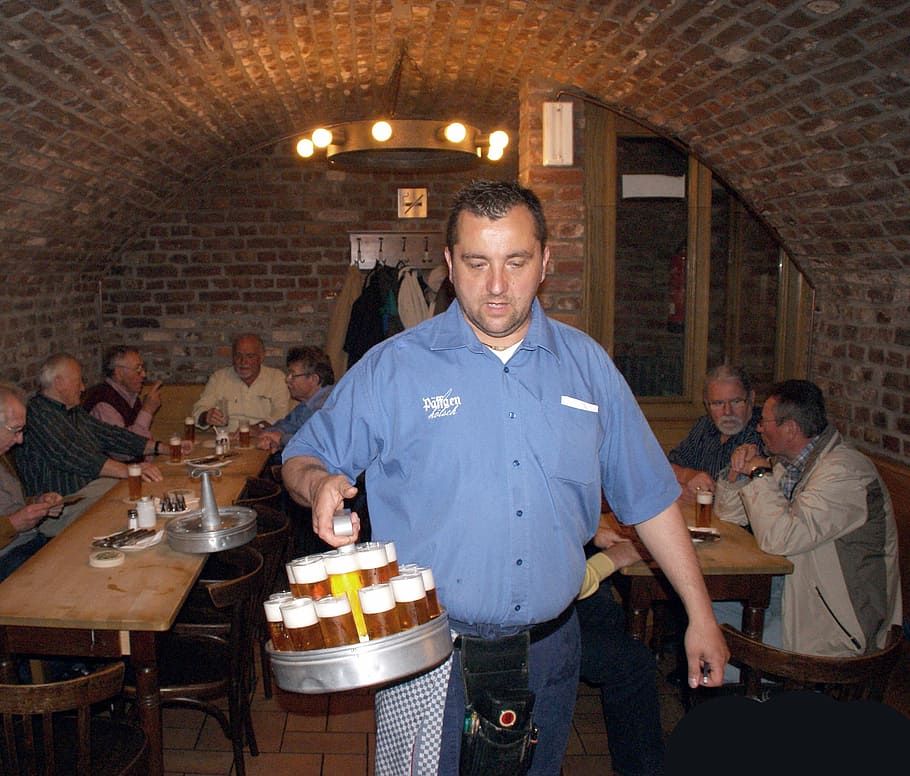 man, wearing, blue, button-up t-shirt, holding, grey, tray, beers, inside, bar