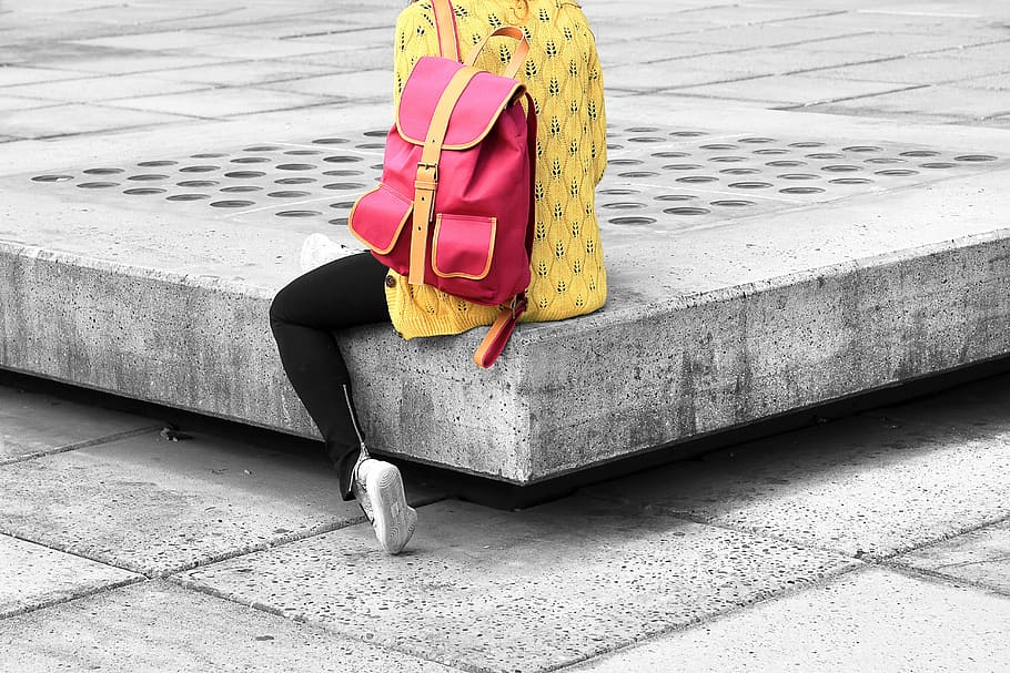 person, sitting, gray, surface, wearing, red, backpack, selective, yellow, shirt