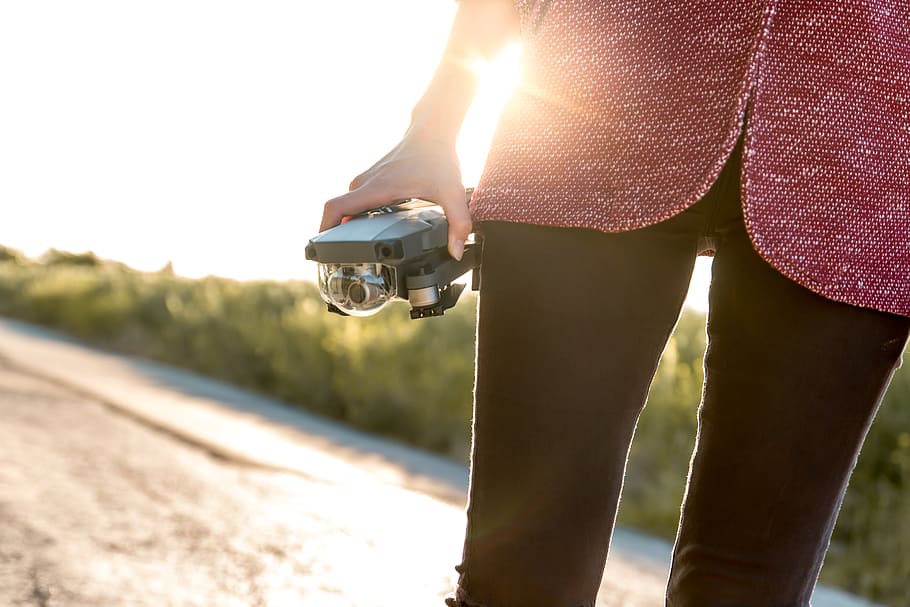 mulher, segurando, drone, ensolarado, estrada, caminho, trilha, tecnologia, viagem, aventura