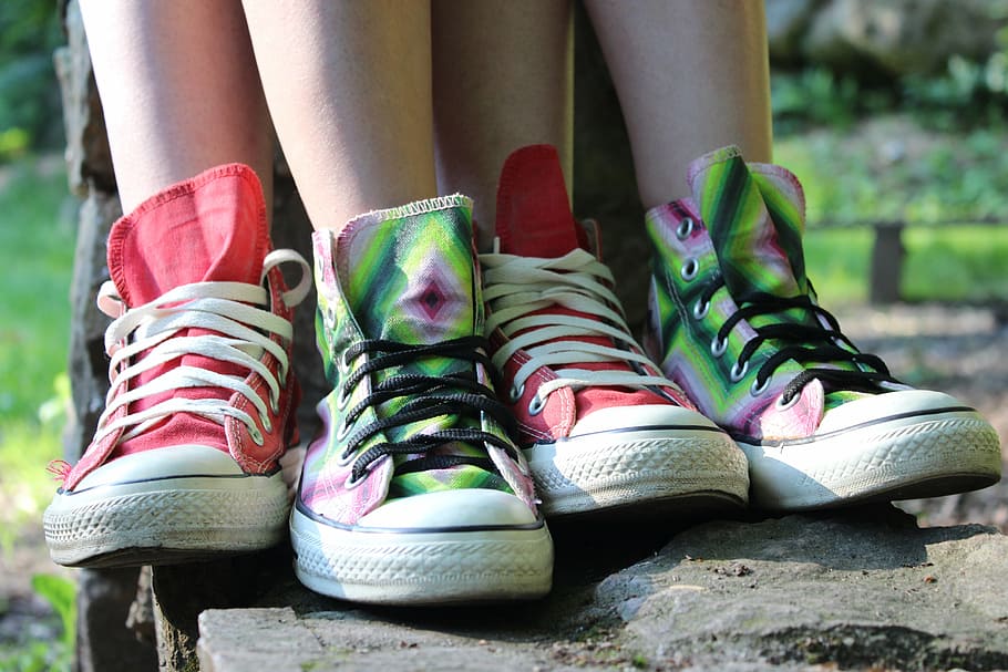 person, wearing, two, pairs, red, green, mid-rise shoes, daytime, converse, sneakers