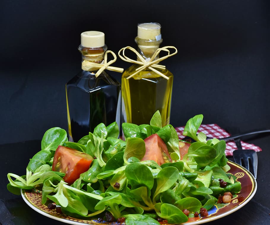 vegetable salad, olive, oil bottles, lamb's lettuce, arugula, bacon, diced bacon, tomato, oil, olive oil