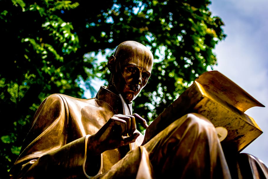 statue, man reading close-up photo, daytime, art, sculpture, gold, nature, trees, sky, book