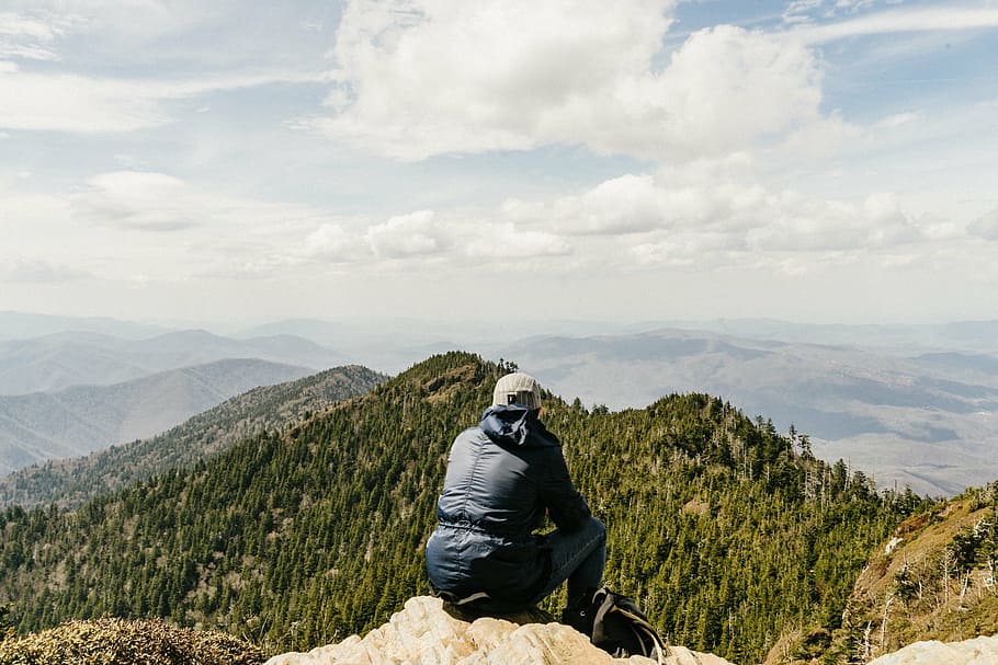 person, sitting, rock, facing, mountain ranges, blue, jacket, denim, jeans, mountain