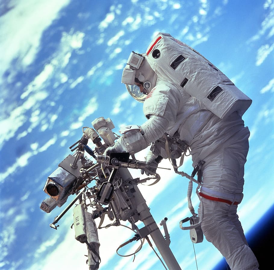 astronaut, holding, machine, planet earth background, spacewalk, space, spacecraft, tools, suit, pack