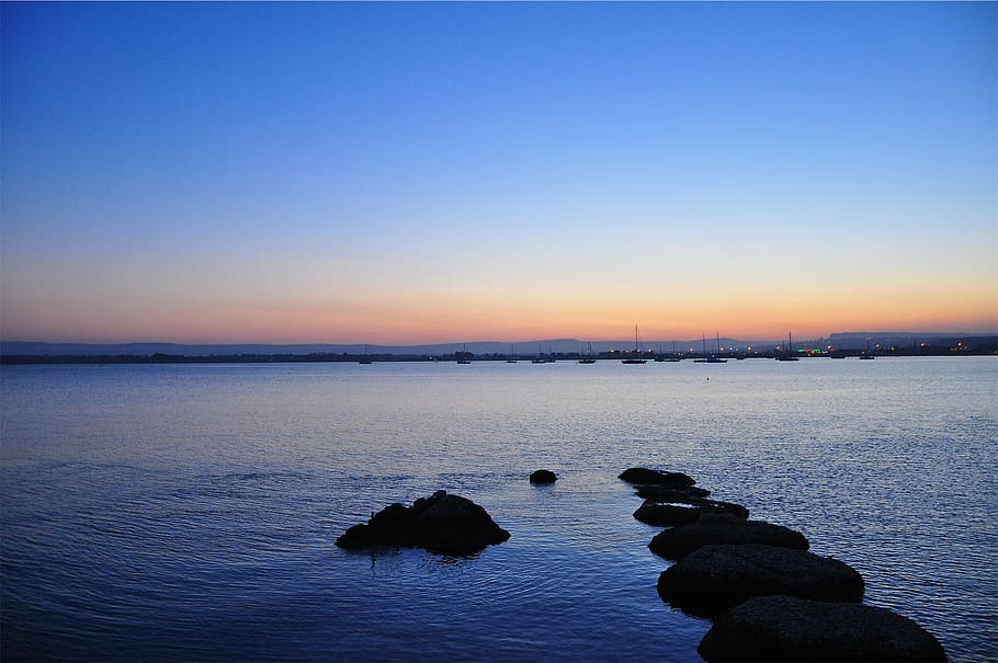 fotografía de paisaje marino, horizonte de la ciudad, puesta de sol, anochecer, oscuro, lago, agua, barcos, muelles, puerto deportivo