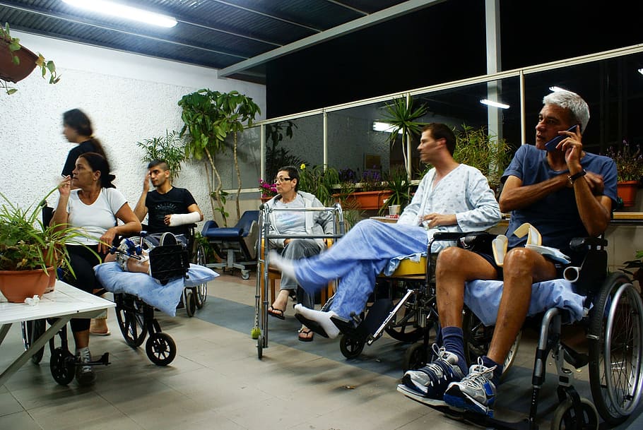 man, wearing, blue, crew neck t-shirt, sitting, black, wheelchair, holding, smartphone, crew neck