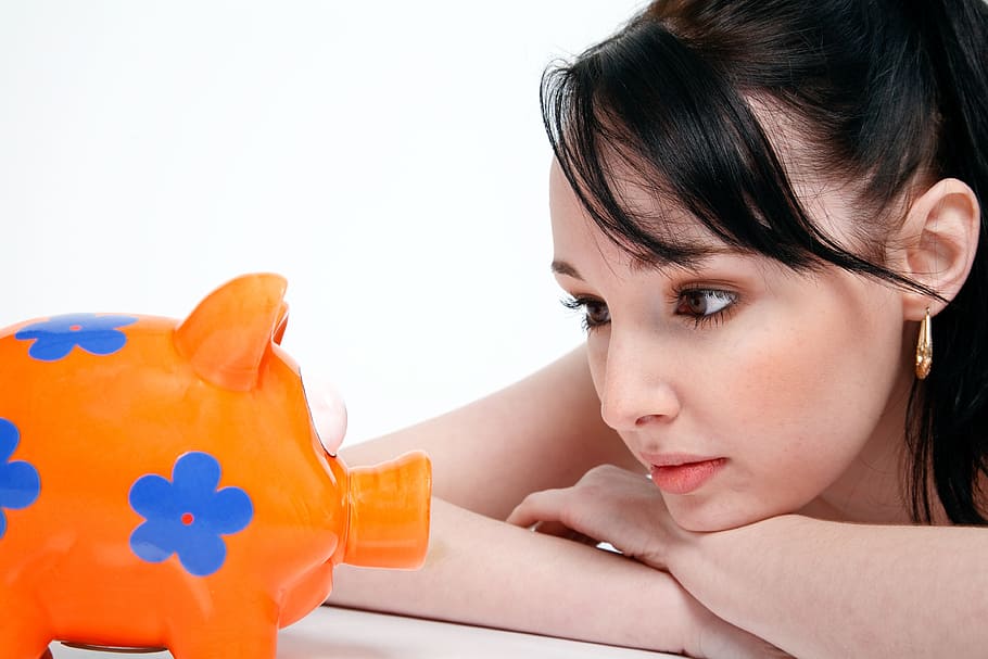 mulher, olhando, brinquedo do porco, economia, dinheiro, jovem, finanças, moeda, investimento, branco