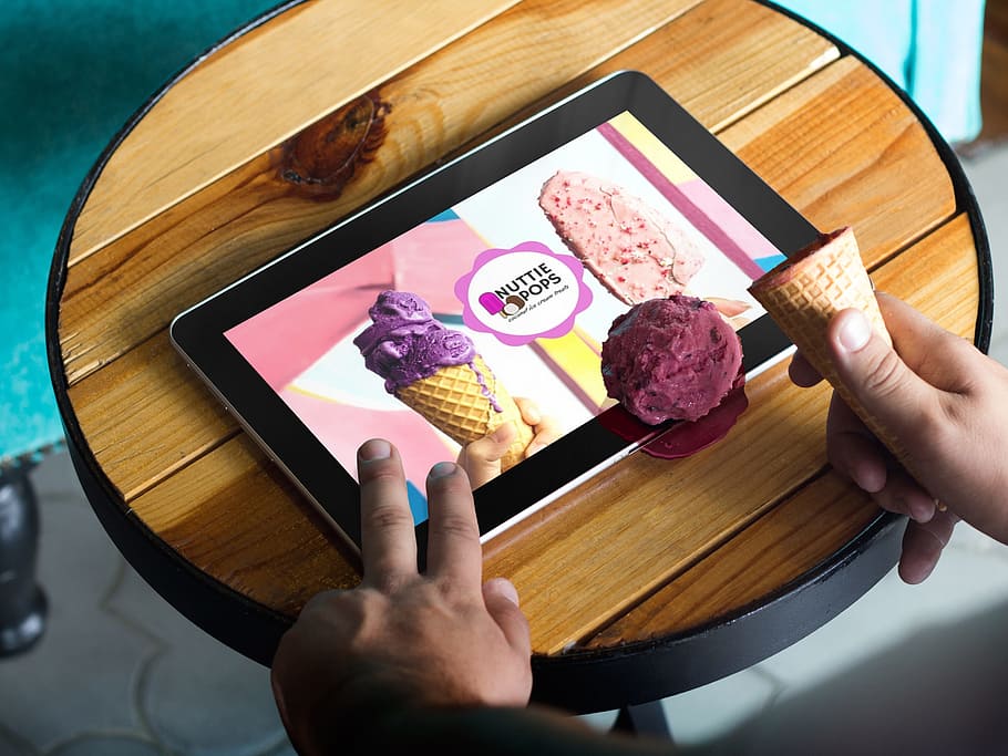 person, holding, tablet computer, showing, nuttie, pops, advertisement, maroon, ice cream, web design