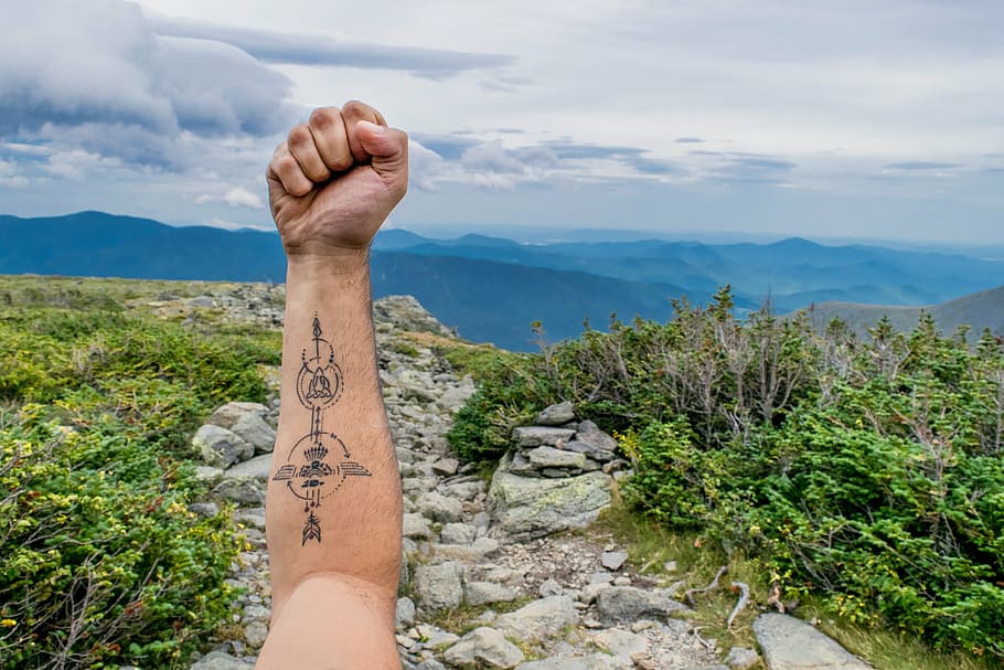 person, raising, arm, tiki totem tattoo, s, tattoo, mountain, highland, rock, trees