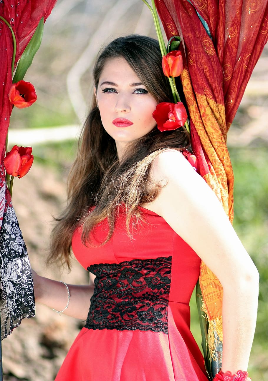 woman, wearing, red, black, floral, sleeveless dress, holding, curtain, flowers, girl