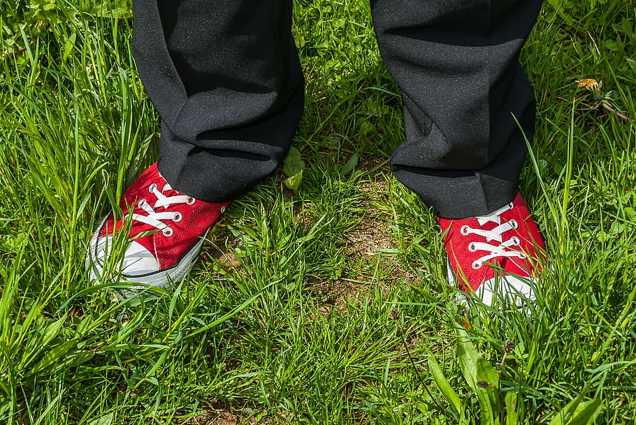 person, standing, grass, daytime, red, red boots, white, white ribbons, white ribbon, black