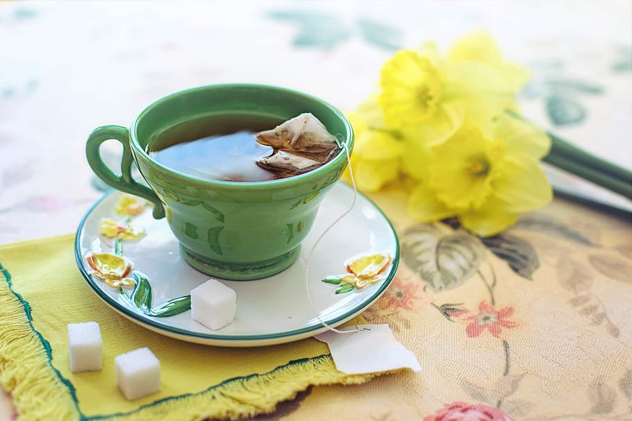almost-filled teacup, tea bag, tea, morning, green, yellow, daffodils, cup, flowers, tabletop