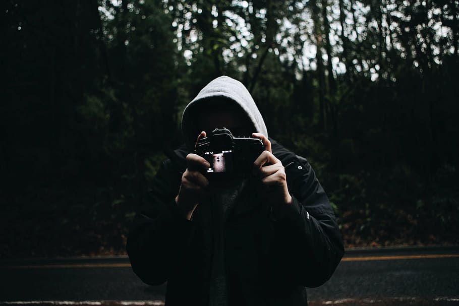 person, wearing, hoodie, holding, camera, road, forest, people, man, dark