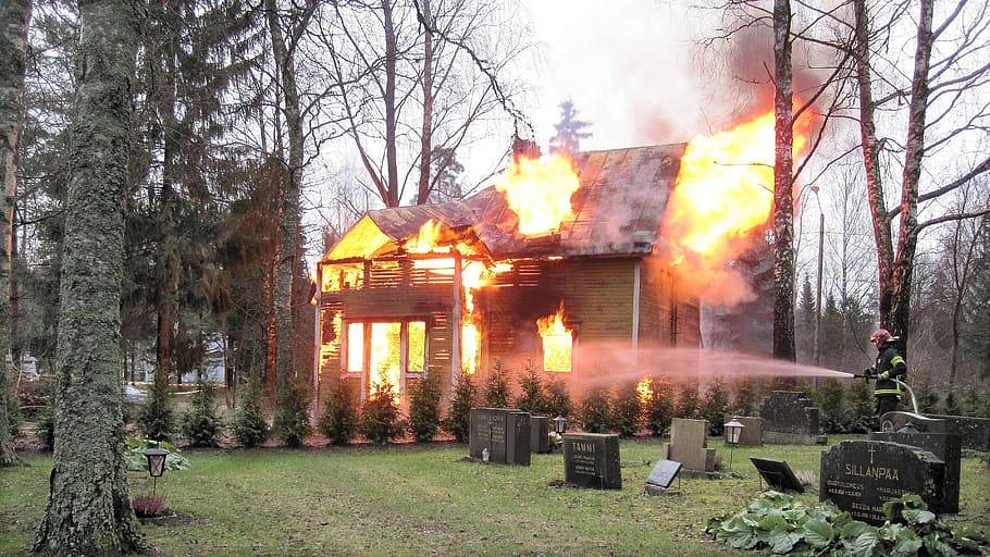 fireman, putting, fire, burning, house, surrounded, trees, tombstones, daytime, house burns